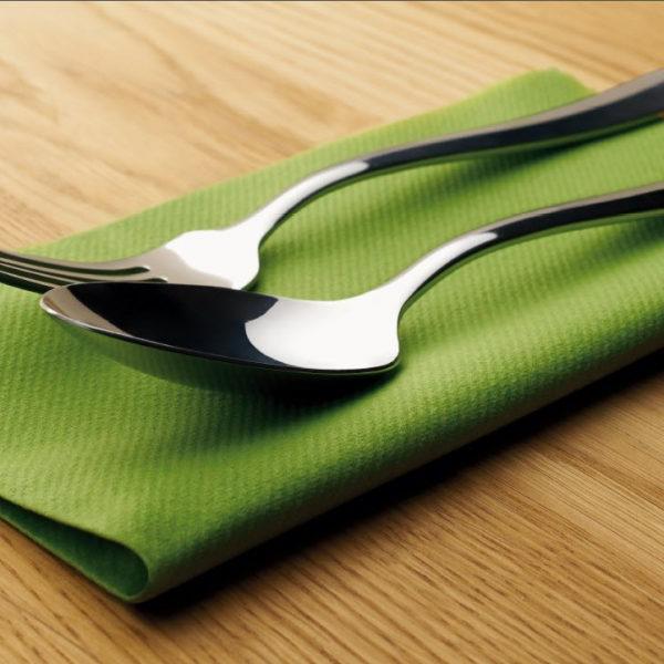 silver spoon and fork on green towel on wood block